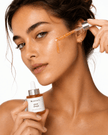 Frau trägt Anti-Aging Glow Drops mit Pipette auf das Gesicht auf
